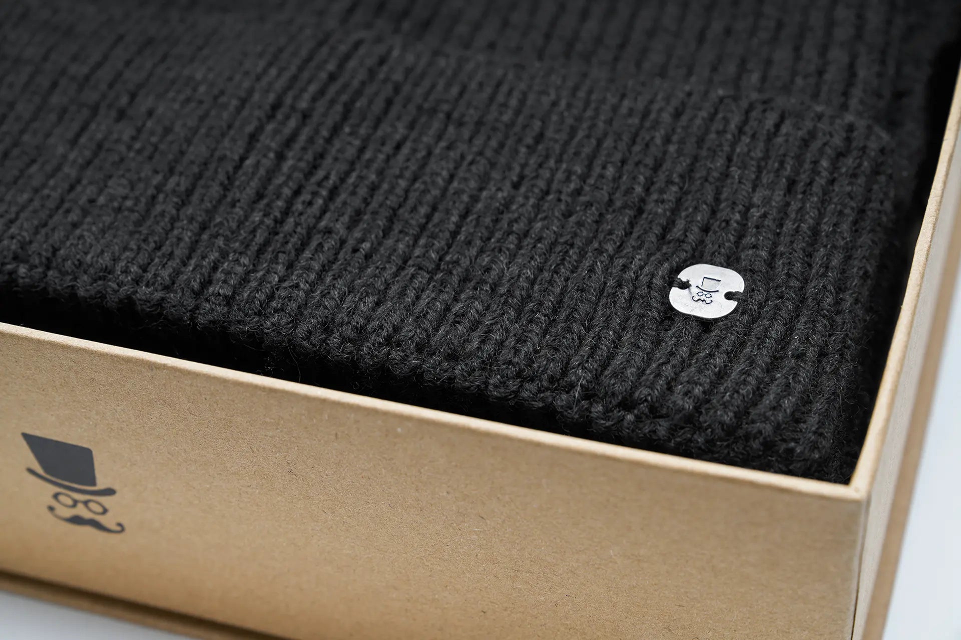 (Schwarz) Herrenschal Mütze Set Wolle – Detailansicht Logo-Pin in Box